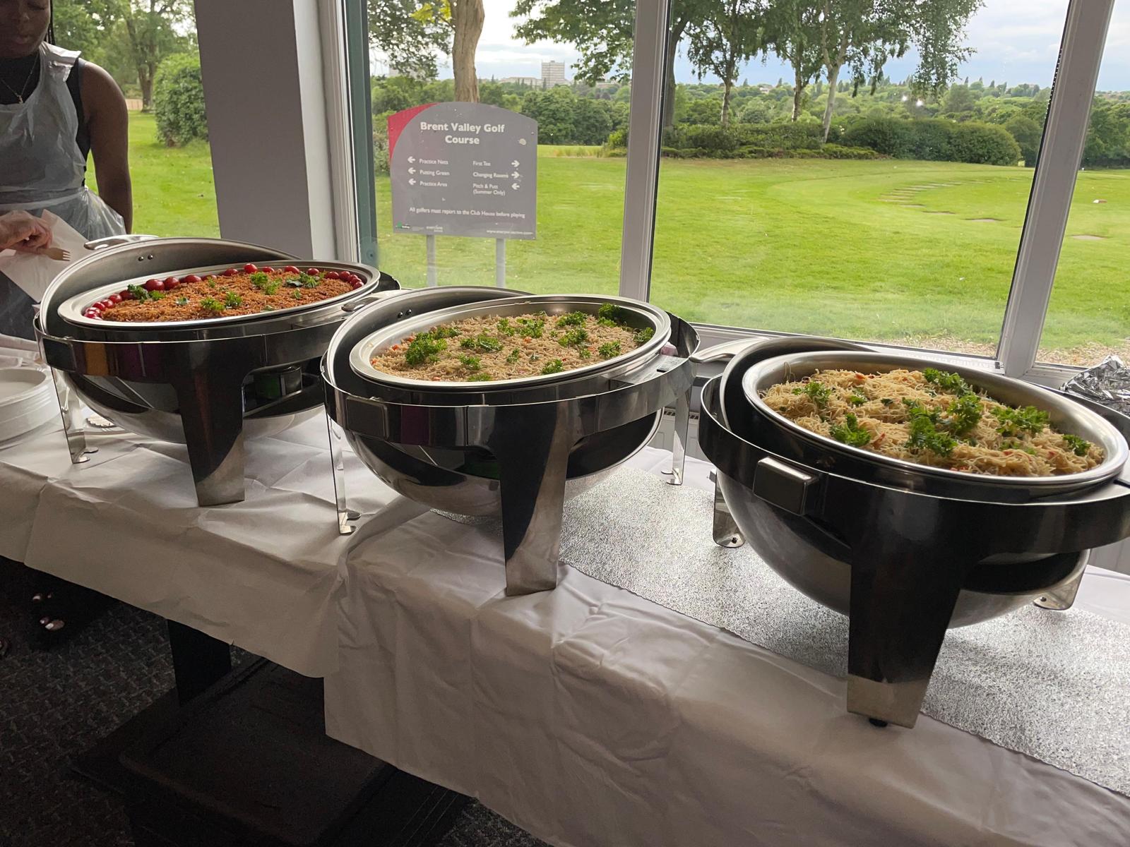 Three chafing dishes of jollof rice, fried rice and noodles at a Brent Valley Golf Course event catered by Cynthia's African Dishes